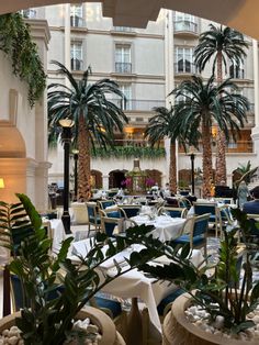 an indoor restaurant with palm trees in the middle and tables set up for people to eat