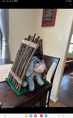 a stuffed animal sitting on top of a wooden table next to a pile of sticks