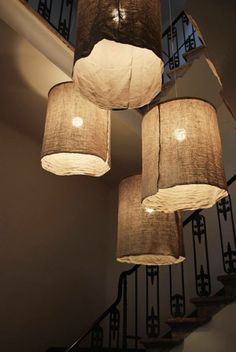 a chandelier with five lamps hanging from it's sides in front of a stair case