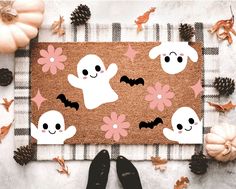 a door mat decorated with halloween ghostes and flowers