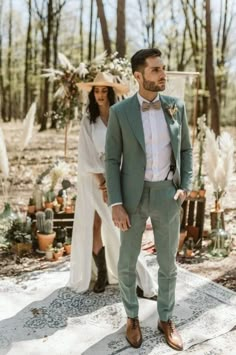 a man in a green suit and bow tie standing next to a woman wearing a white dress