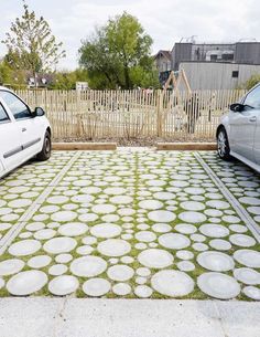 two cars parked in front of a fence with grass growing on the ground next to them