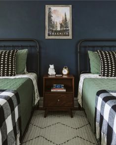 two twin beds in a bedroom with blue walls and plaid blankets on the bedding