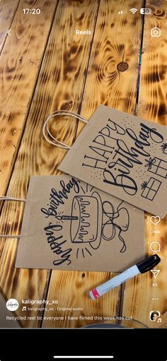 two brown paper bags sitting on top of a wooden table next to marker pens and markers