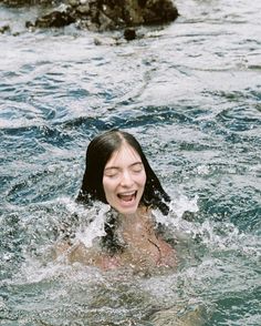 a woman is swimming in the water with her eyes closed and mouth wide open,