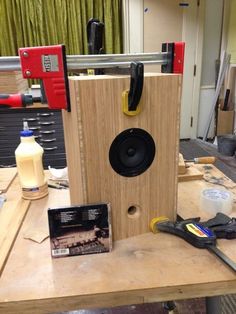 a wooden speaker sitting on top of a table next to tools and other items in front of it