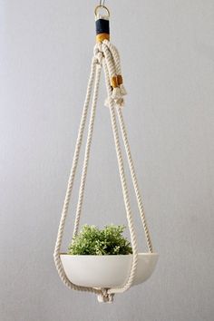 a white hanging planter filled with green plants