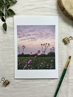 a card with pink flowers on it next to a green pencil and some other items