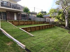 a backyard with grass and wooden steps leading up to the decked in lawn area