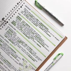 a notepad and pen sitting on top of an open spiral bound notebook next to a green marker