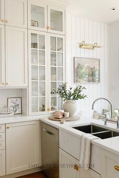 a kitchen with white cabinets and marble counter tops is pictured in this image, the sink has a dishwasher next to it