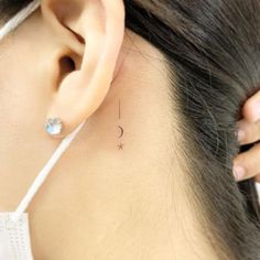 a woman's ear has a tiny star and moon tattoo on it