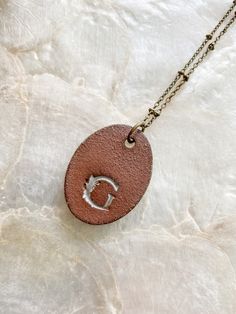 This handmade oval clay pendant is imprinted with the seeds of a Sea Oat plant (Uniola paniculata) collected from the Texas coast then finished with a rustic white glaze. Pendant measures roughly 1"x1.5" and is on a 24" antiqued brass satellite chain with lobster clasp closure. Included tag has species name and back of pendant has a small "G" logo. Necklace will ship on a card in a muslin bag then packaged within a protective envelope. *NOTE* brass chain can be prone to discoloration if exposed Oat Plant, Sea Oats, Ceramic Pendant Necklace, Texas Coast, Logo Necklace, Sea Design, Muslin Bags, Ceramic Pendant, Green Sea