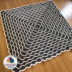 a black and white crocheted rug on a wooden floor