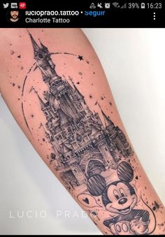 a person with a tattoo on their arm that has a castle and mickey mouse in it