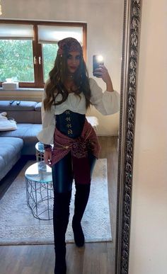 a woman taking a selfie in front of a mirror wearing pirate costume and holding a cell phone