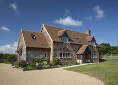 a large brick house sitting on top of a lush green field next to a wooden fence