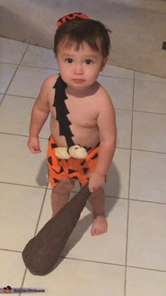 a baby in a costume standing on the floor