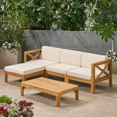 a wooden couch sitting on top of a stone floor next to a table and potted plant