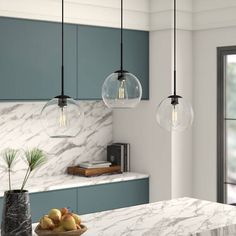 a kitchen with marble counter tops and blue cabinets, hanging lights above the island table