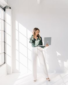 a woman standing in an empty room using a laptop