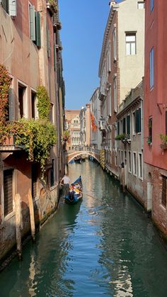 a small boat traveling down a narrow canal between two buildings on both sides with green shutters