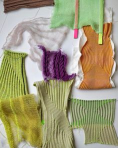 several different colored knitted items laid out on a white surface, including socks and yarn