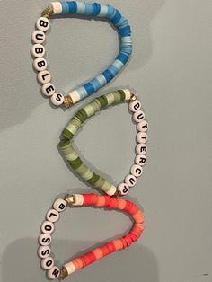 three bracelets hanging on the wall with words written in different colors and sizes,