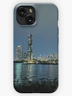 the city skyline is lit up at night with lights reflecting in the water iphone case