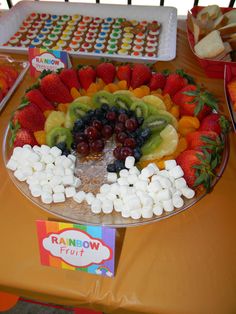 a platter filled with fruit and marshmallows on top of a table