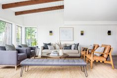 a living room with couches, chairs and coffee table in front of large windows