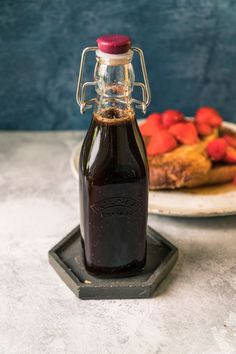 a bottle of syrup sitting on top of a plate next to strawberries and bananas