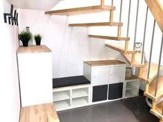 a room with some shelves under the stairs and a plant on top of one shelf