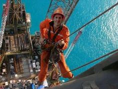 a man in an orange safety suit and white helmet on a rope