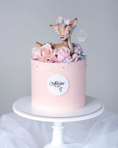 a pink cake decorated with flowers and a deer figurine sitting on top of it