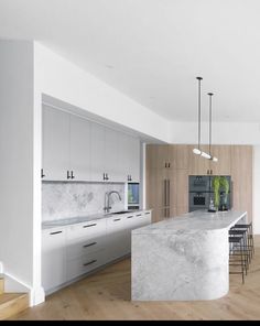 a large kitchen with marble counter tops and white cabinets, along with bar stools