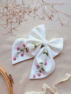 two white bows with pink flowers on them sitting next to some crochet lace