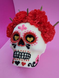 a white skull with red flowers on it's head and hair pins in its ears