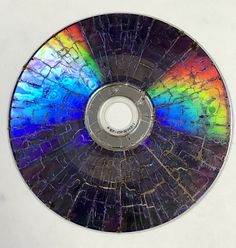 a multicolored cd disc sitting on top of a white surface with holes in it