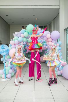 three women dressed in costumes standing next to balloons