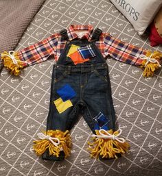 a toddler's overalls and plaid shirt are laying on a bed