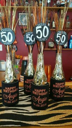 three vases filled with gold and black birthday candles