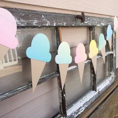 some ice cream cones are hanging on a window sill with paper flags attached to it