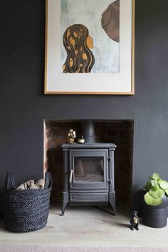 a living room with a wood burning stove next to a basket and painting on the wall