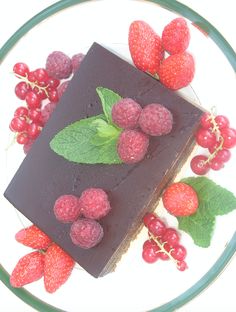 a piece of chocolate cake with raspberries and mint leaves