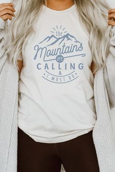 Introducing our "The Mountains Calling And I Must Go" Graphic Tee, a perfect choice for adventure enthusiasts and outdoor lovers. Most t shirt colors are 52/48 cotton/poly blend. White and Cream tees are 100% cotton, Ash tees are 99/1 cotton/poly. Available in various sizes, it's an excellent addition to outdoor retail stores and adventure-themed boutiques. Encourage your customers to answer the call of the mountains with our "The Mountains Calling And I Must Go" Graphic Tee. By Kissed Apparel.M T Shirt Colors, Pink Canvas, The Mountains Are Calling, Outdoor Lover, Retail Stores, Heather Black, White Cream, Men's Collection, Dress Accessories