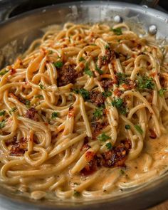 a bowl filled with pasta and sauce on top of a wooden table