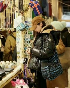 a woman looking at her cell phone while standing in front of a store with other people