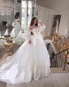 a woman in a white wedding dress taking a selfie with her cell phone while standing on stairs