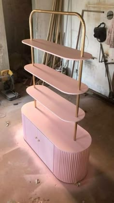 three tiered pink and gold shelf in a garage